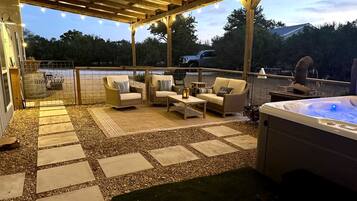 An outdoor patio with seating, a hot tub, and a view of the landscape.
