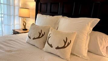 Een bed met witte beddengoed en twee sierkussens met rendierhoorns.