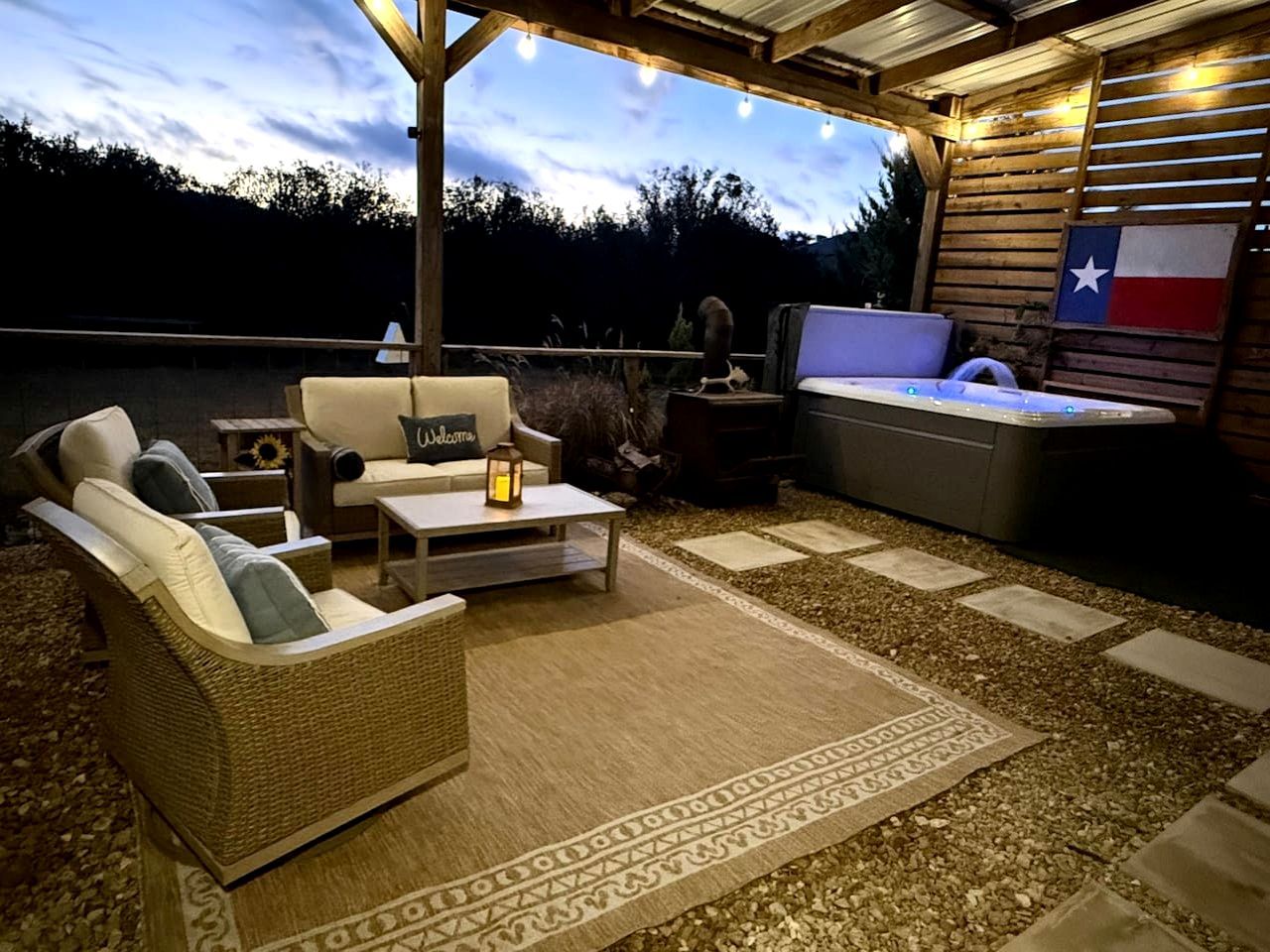 An outdoor patio area with wicker furniture, a hot tub, and a Texas flag.