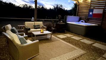 An outdoor patio area with wicker furniture, a hot tub, and a Texas flag.
