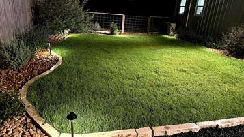 A well-maintained lawn with a stone border and a garden bed with rocks and plants.