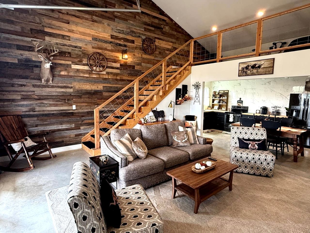 A rustic interior with a wooden staircase, a sofa set, and a dining area.