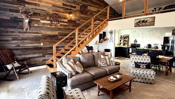 A rustic interior with a wooden staircase, a sofa set, and a dining area.