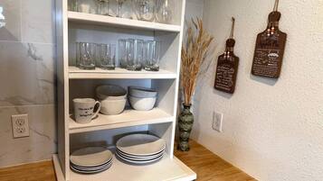 A kitchen shelf with glassware, bowls, and plates.