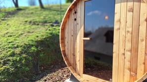 A wooden structure with a circular door and a small window, surrounded by grass and a clear sky. - A cozy stay with panoramic views for two, featuring a barrel sauna (Durbuy)