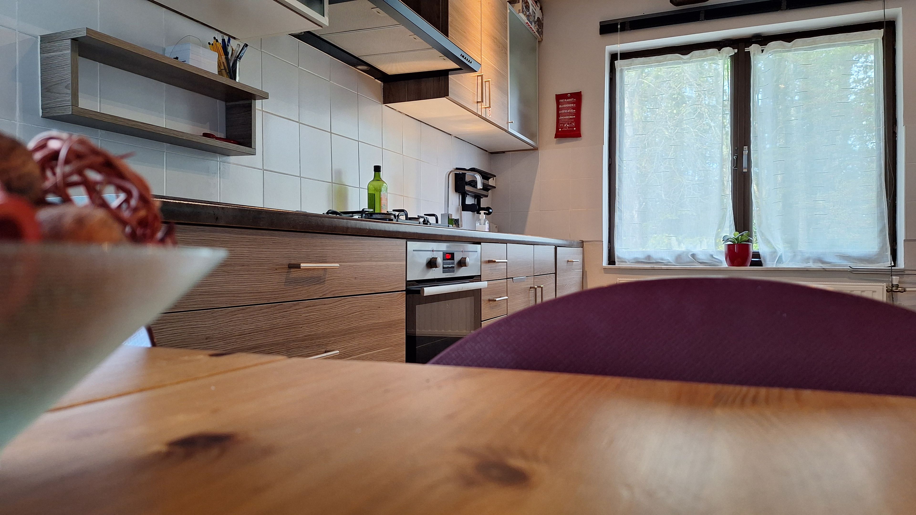 A modern kitchen with wooden cabinets, a built-in oven, and a window with a view.