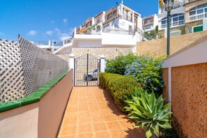 A residential area with a gated entrance, a tiled pathway, and a variety of plants. - Holiday Home in Nerja With Sea Views (Nerja)