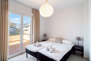A hotel room with a bed, two bedside lamps, a large window with curtains, and a view of the city. - Holiday Home in Nerja With Sea Views (Nerja)