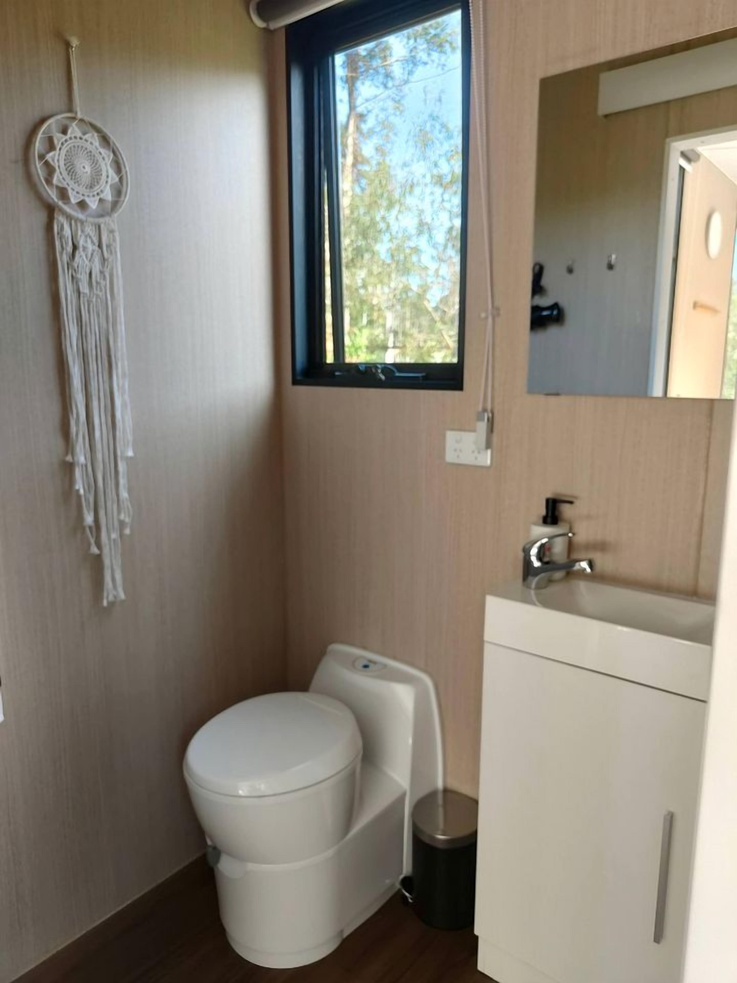 Een kleine badkamer met toilet, wastafel en een dromenvanger aan de muur.