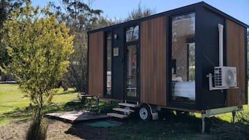 Ein modernes, kompaktes Wohnmobil mit Schiebetür, kleiner Terrasse und sichtbarer Klimaanlage.