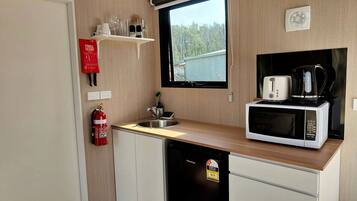 Eine kompakte Küchenzeile mit Mikrowelle, Toaster und Kaffeemaschine auf der Arbeitsfläche.