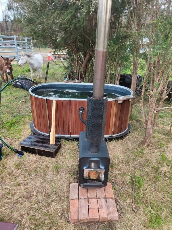Un jacuzzi con revestimiento de madera, una chimenea de metal y una base de ladrillo.