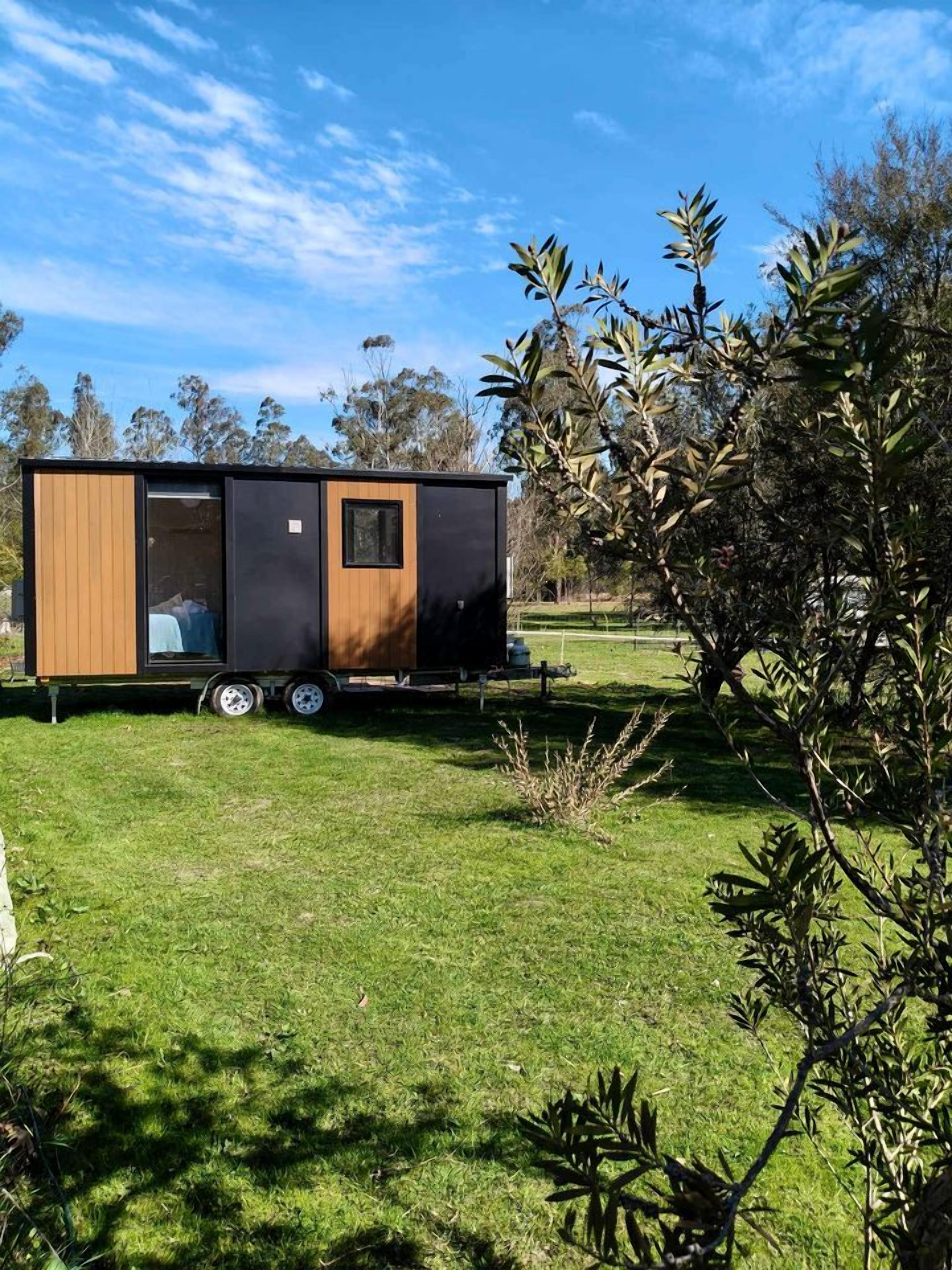 Une maison mobile moderne dotée d’une porte coulissante, d’une petite fenêtre et d’un toit plat.