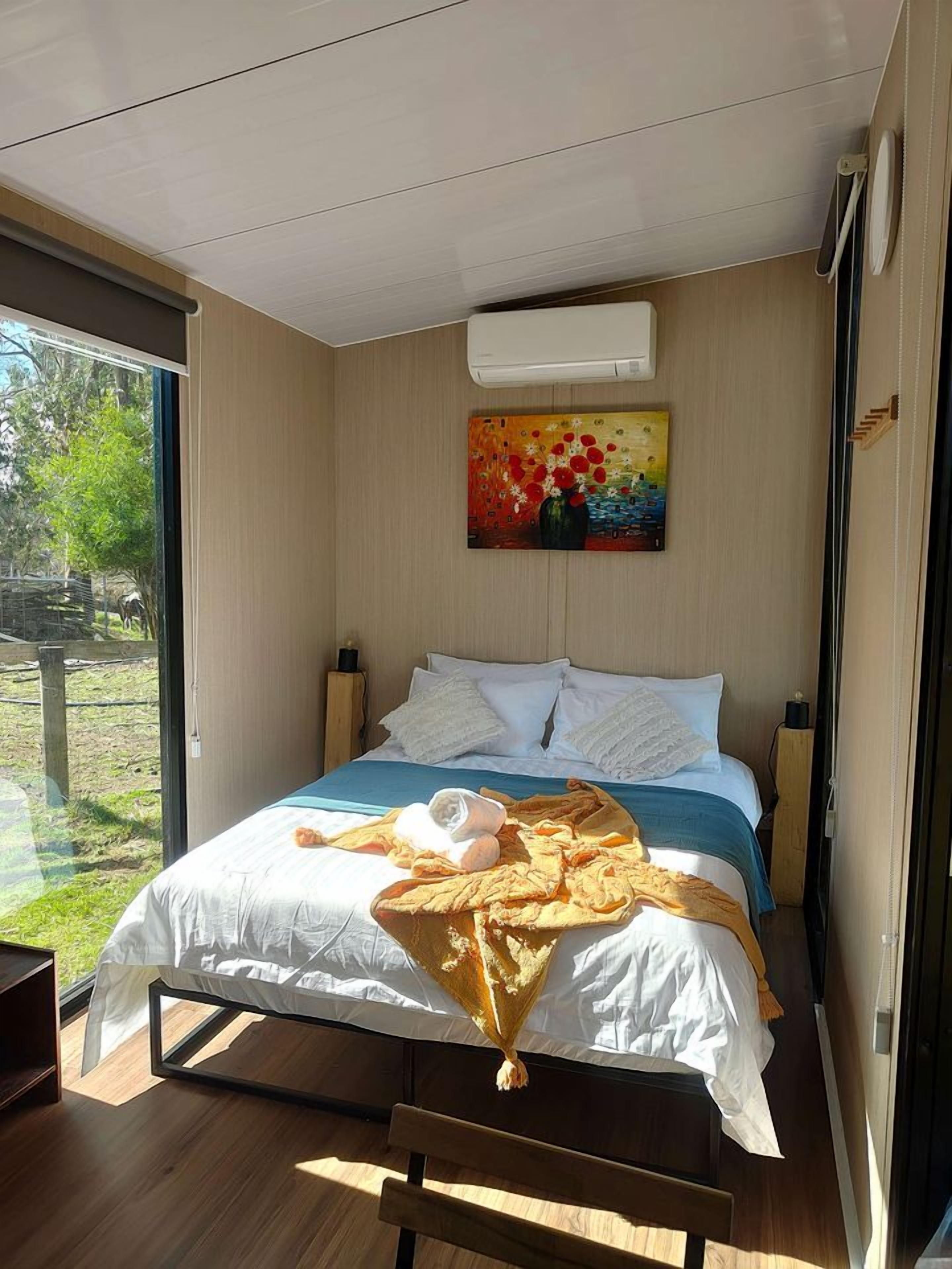 Een moderne slaapkamer met een groot bed, een schilderij en uitzicht op het landschap.