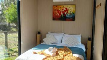 Een moderne slaapkamer met een groot bed, een schilderij en uitzicht op het landschap.