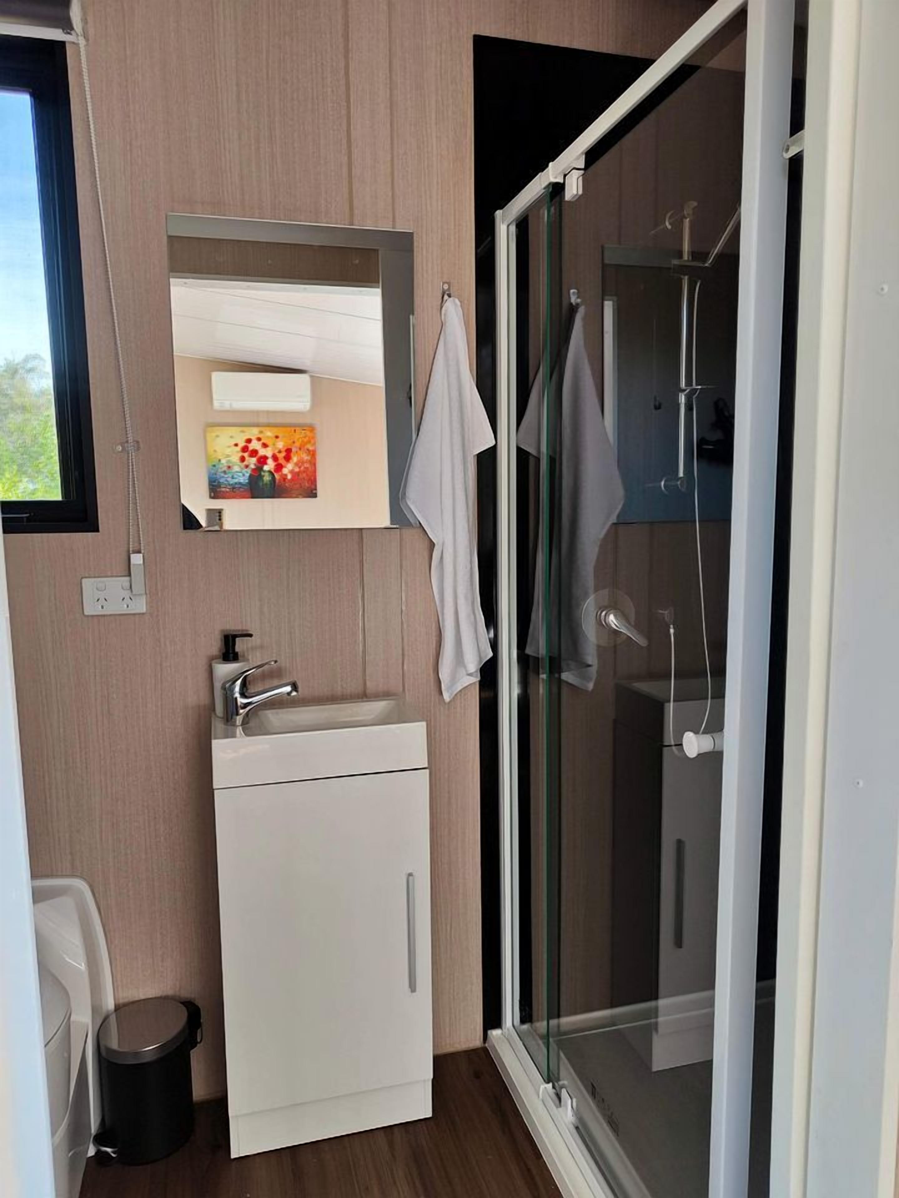 Une salle de bain moderne avec une douche à parois de verre, un lavabo blanc et un miroir au-dessus.