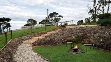 A landscaped outdoor area with a fire pit, seating, and a pathway leading uphill.
