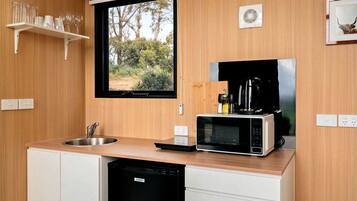 A compact kitchen with a built-in microwave, a coffee maker, and a window overlooking a natural landscape.