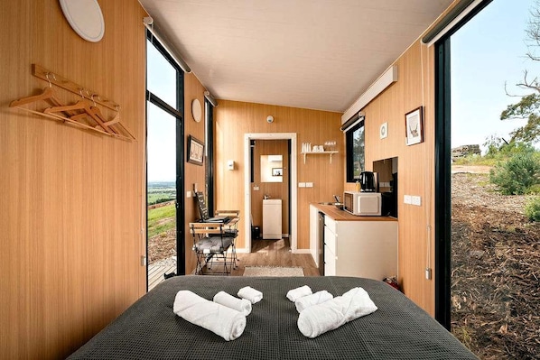 A room with a bed, a small kitchenette, and a view of the outdoors.