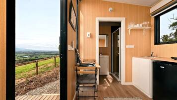 A modern kitchen with a view of a green landscape, a wooden dining area, and a black dishwasher.