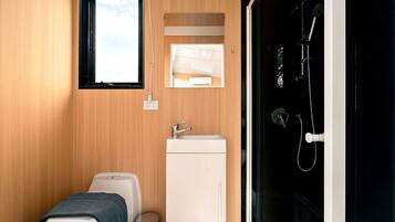 A compact bathroom with a toilet, sink, and shower area.