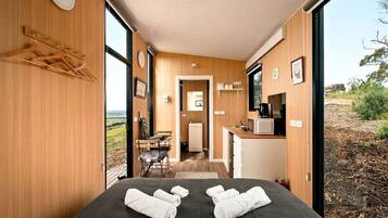 A room with a bed, a small kitchenette, and a view of the outdoors.