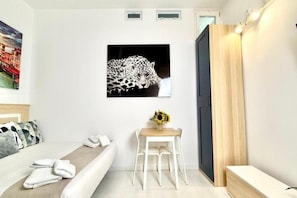 Una habitación de hotel con una cama, un escritorio con una silla, un cuadro de un leopardo y una puerta de madera.