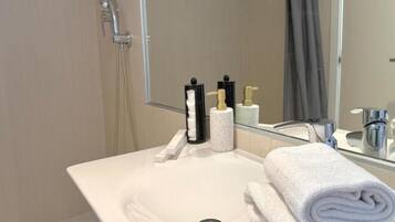 A bathroom with a white sink, a mirror, a towel, and toiletries.