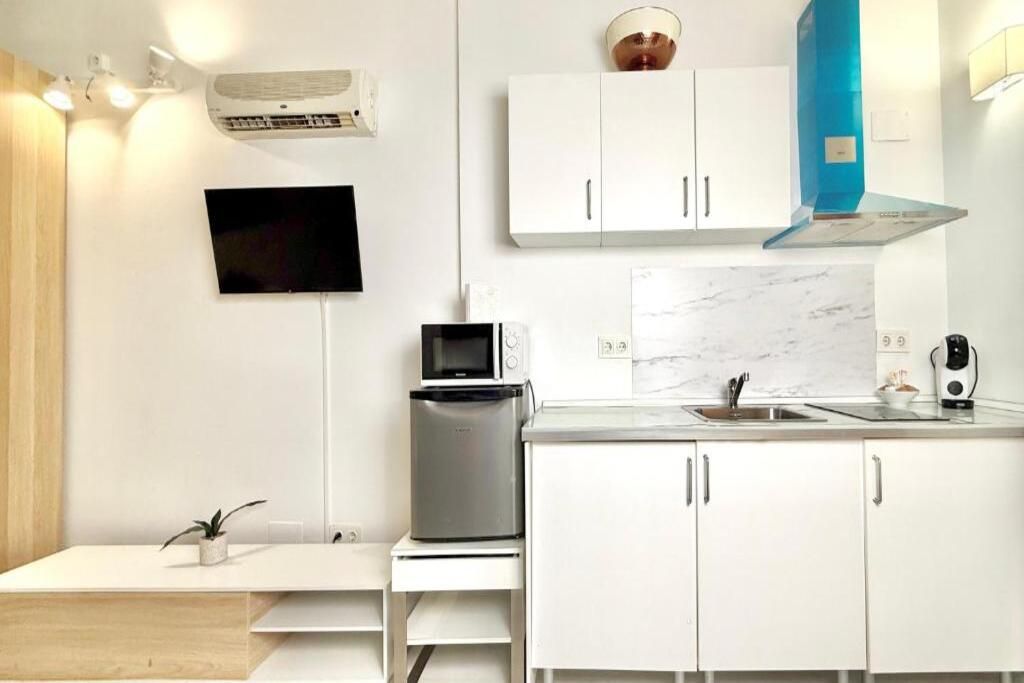 Une cuisine moderne avec des meubles blancs, un four à micro-ondes encastré, une machine à café et un évier.
