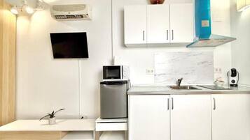 Une cuisine moderne avec des meubles blancs, un four à micro-ondes encastré, une machine à café et un évier.