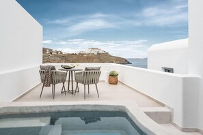 A rooftop terrace with a pool, two chairs, a table, and a view of a coastal landscape. - Saluti Da Stampalia (Astypalaia)