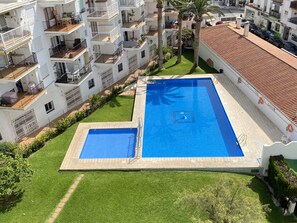 Ein Wohngebäude mit Schwimmbad, Balkonen und Garten.