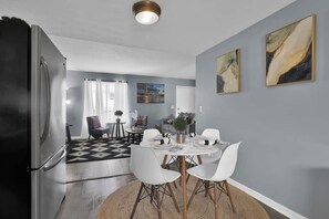 A modern kitchen with a refrigerator, dining table with chairs, and a rug. - Jackie's Green Parkside Mansfield Townhouse (Mansfield)