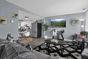 A modern living room with a sofa, coffee table, and a view into the kitchen. - Jackie's Green Parkside Mansfield Townhouse (Mansfield)