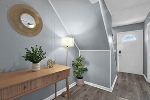 A hallway with a wooden console table, a floor lamp, and a potted plant. - Jackie's Green Parkside Mansfield Townhouse (Mansfield)