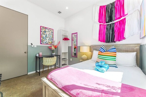 A hotel room with a bed, bedside table, chair, desk, and a wardrobe.