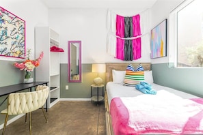 Una habitación de hotel con cama, escritorio, silla, espejo y ventana.