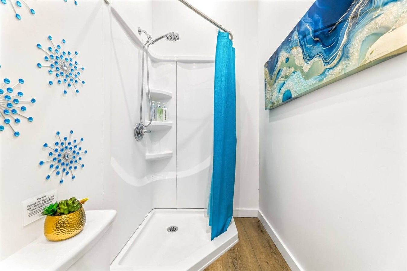 A shower with a blue curtain, a white sink, and a wall-mounted shelf with toiletries.