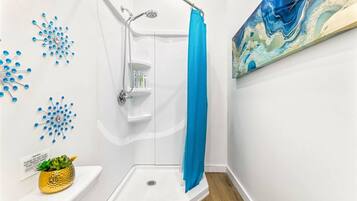 A shower with a blue curtain, a white sink, and a wall-mounted shelf with toiletries.