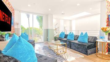 A modern living room with a sofa set, a coffee table, and a TV mounted on the wall.