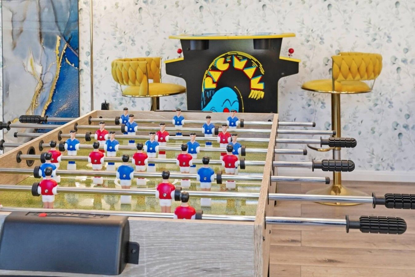 A foosball table with a black and yellow cabinet in the background.