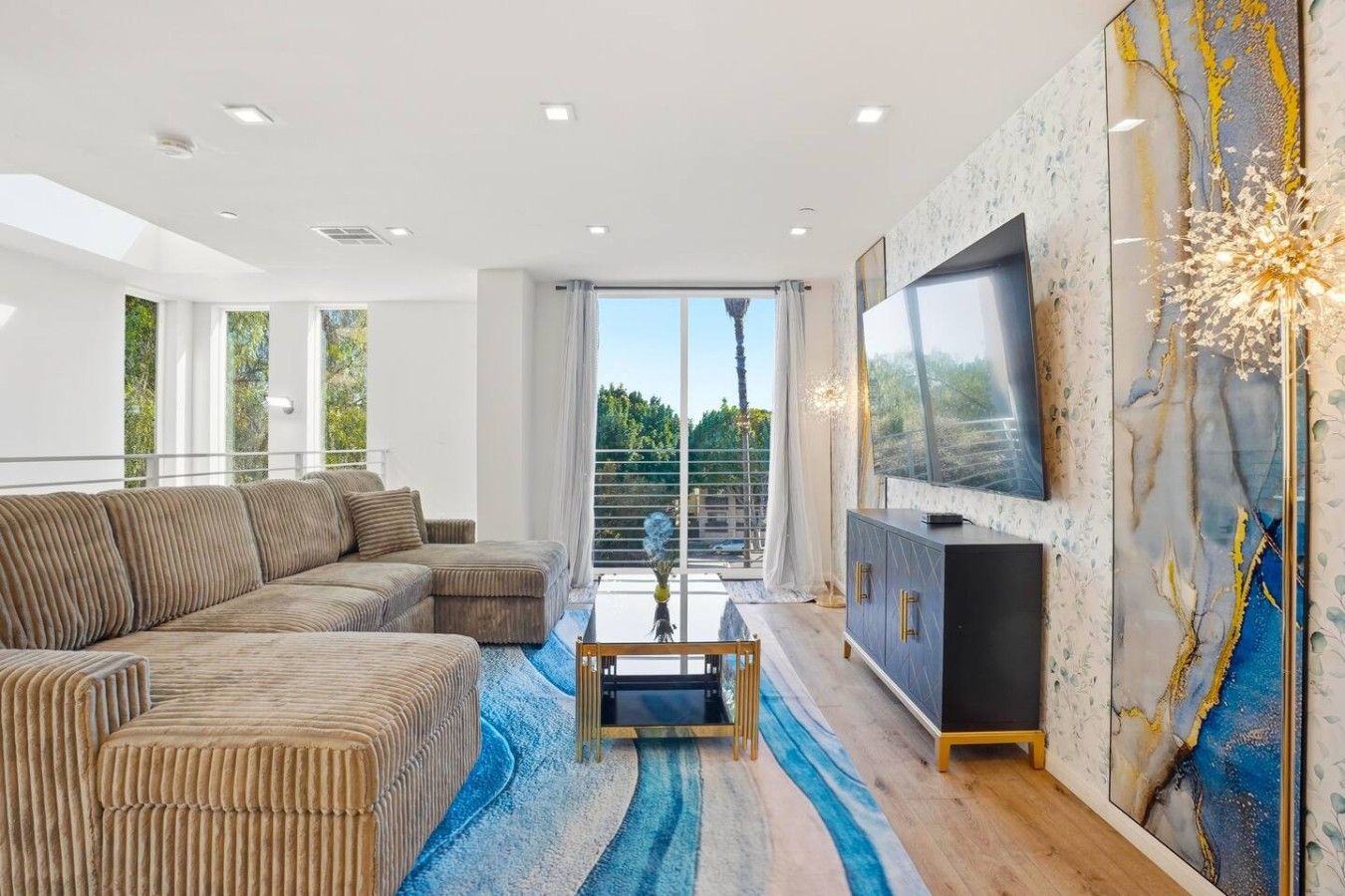 Una sala de estar moderna con un sofá modular, un televisor de pantalla plana y un adornado receso en la pared.
