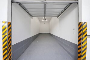 A clean, empty hallway with a grey floor and white walls, flanked by yellow and black striped safety barriers.