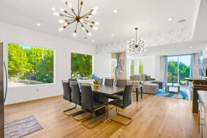 A modern interior with a dining area, sofas, and a kitchen.