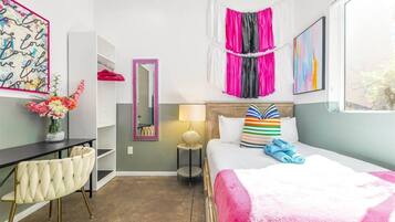 A hotel room with a bed, a desk, a chair, a mirror, and a window.