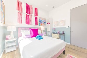 A hotel room with a large bed, a bedside table, a nightstand, a wardrobe, and a wall with artwork.