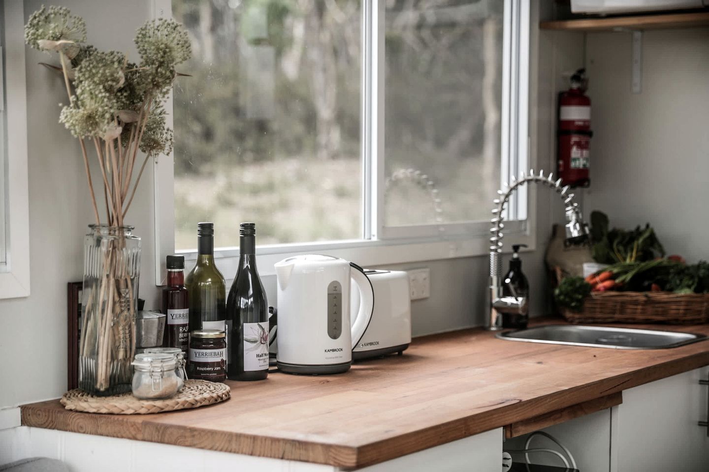 Una encimera de cocina con una cafetera, botellas y frascos.