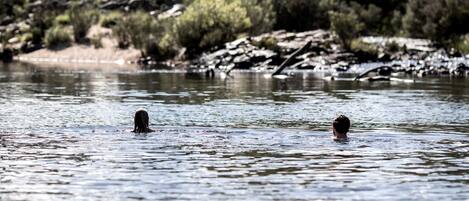 A river with two individuals swimming.