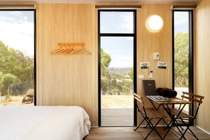 Un dormitorio con una cama, un escritorio con una computadora portátil y vistas al exterior.