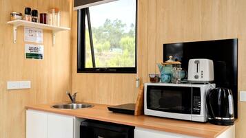 Une cuisine compacte équipée d’un évier, d’un four à micro-ondes, d’un grille-pain et d’une machine à café, le tout placé sur le plan de travail.